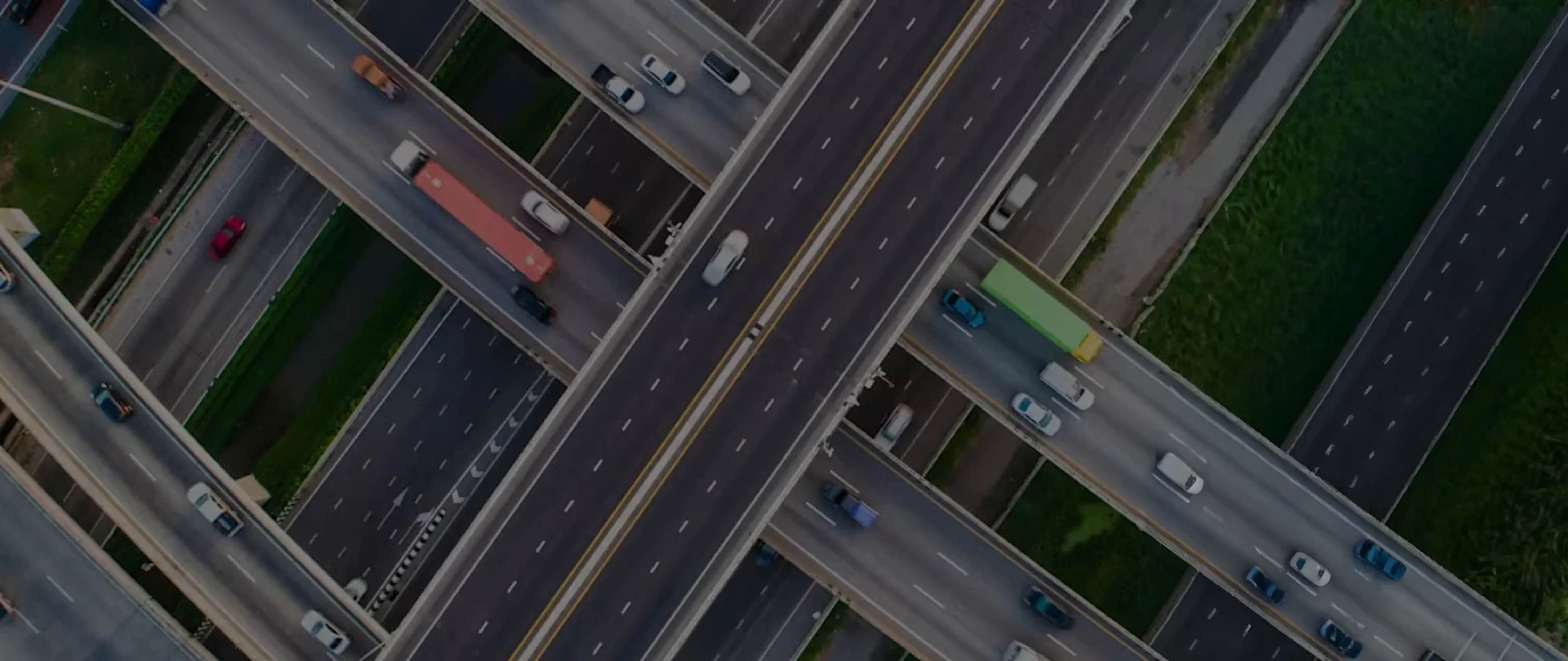 Aerial view of a complex, multi-level highway interchange with cars and trucks traveling on intersecting overpasses and roads.