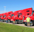 Four men stand in front of a line of red PJ Food Service semi-trucks parked outside on a clear day.