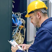 Homme en casque jaune utilisant une tablette près d'une salle de serveurs
