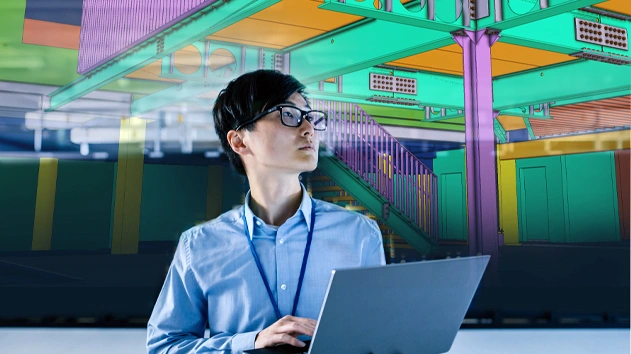 A professional with a laptop views a digital 3D structural model overlay, illustrating Trimble’s BIM and digital construction technology.