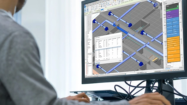 A person works in Stabicad for Revit, showing a 3D MEP model of blue piping and a calculation results window on a computer screen.