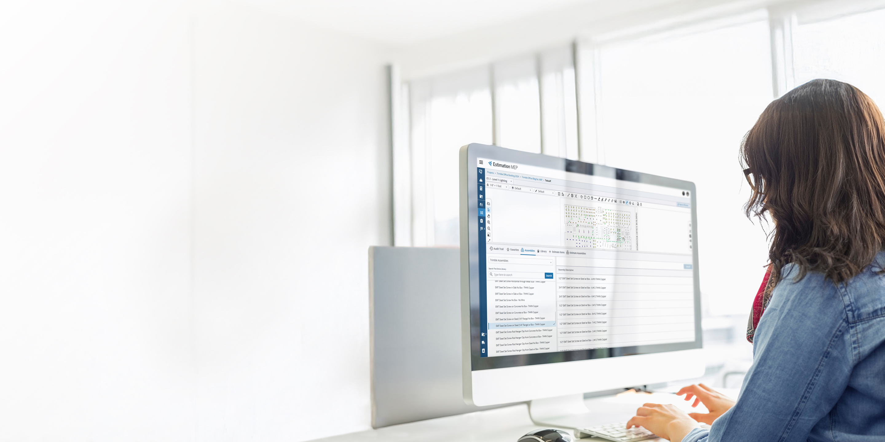 A person's back is to the camera while they work at a desk, looking at the Estimation MEP interface on a desktop monitor.