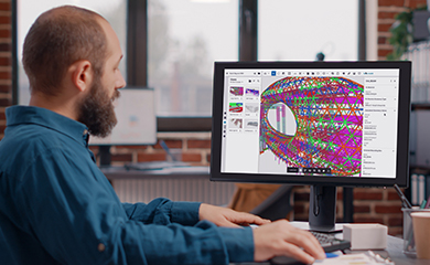 A man uses Trimble's Tekla Structures software to design a complex 3D structural model on a computer in a modern office.