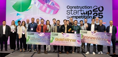 A group of award winners holding large ceremonial checks on stage at the 2025 Construction Startup Competition.