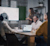 A diverse team of professionals in an office meeting with a laptop displaying a Trimble Construction One analytics dashboard.