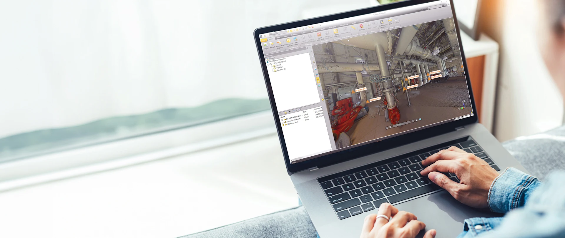A person uses Trimble RealWorks software on a laptop to analyze a 3D point cloud scan of an industrial facility with station markers.