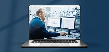 Laptop displaying a professional working with construction estimating software on dual monitors in an office.