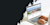 Eine Person in einem weißen Hemd benutzt einen Laptop, auf dem eine farbenfrohe Webseite mit Stadtansichten zu sehen ist. Die Atmosphäre ist hell und minimalistisch.