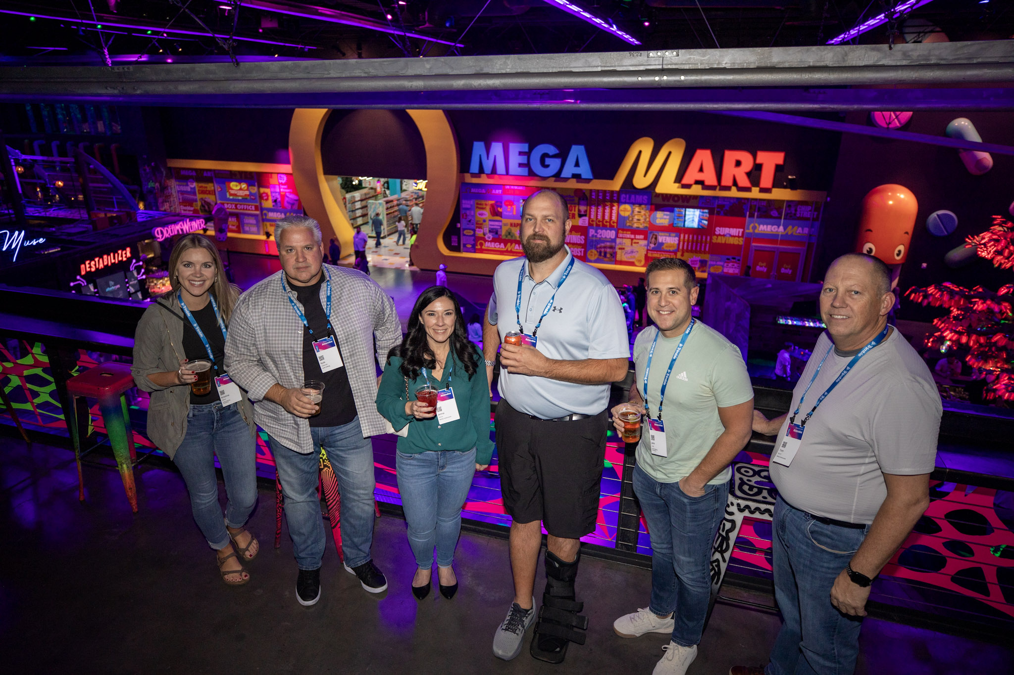  Trimble Dimension attendees pose and smile for a photo outside of the Omega Mrt Meow Wolf installation at AREA15.