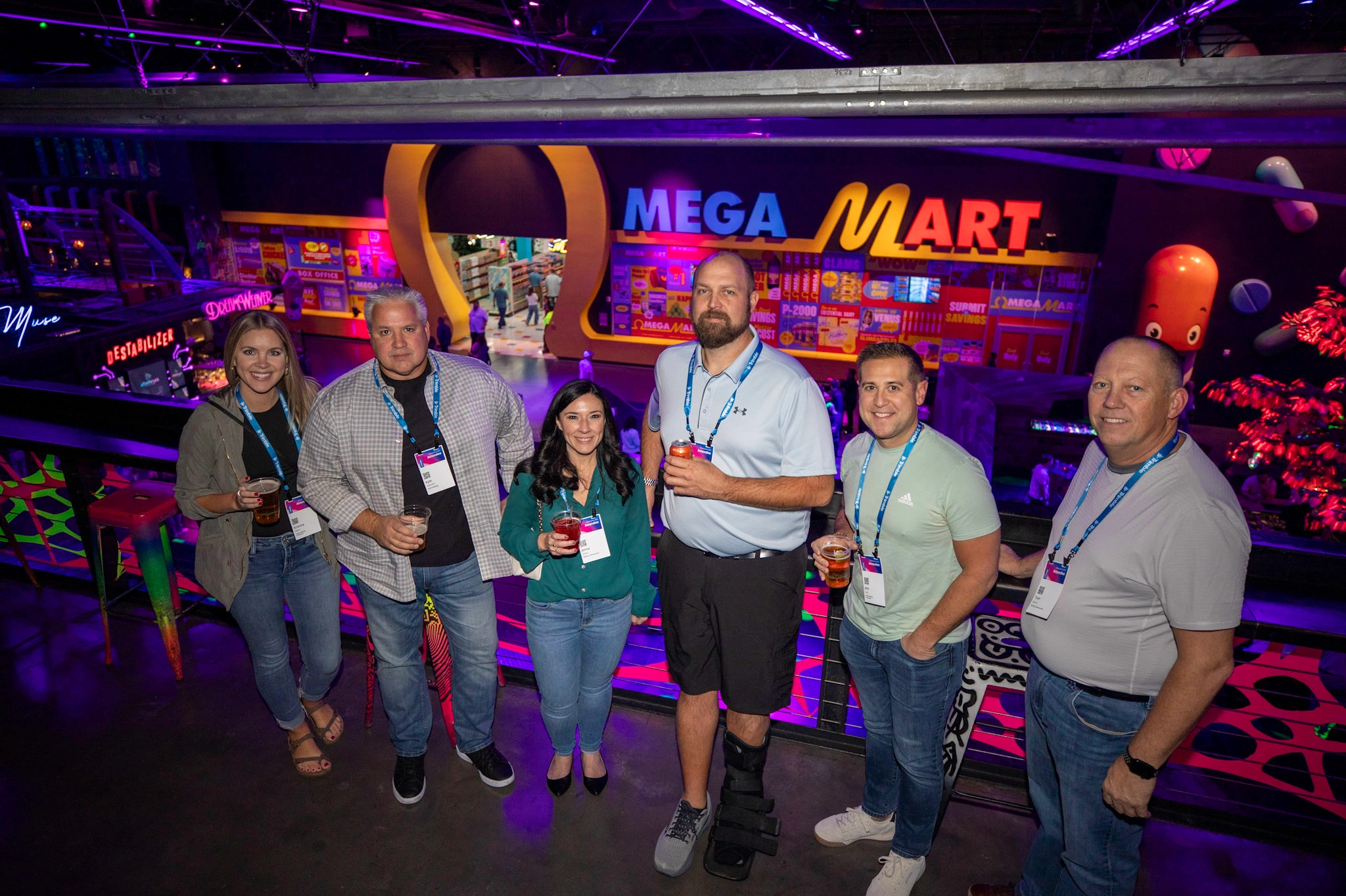 Trimble Dimension attendees pose and smile for a photo outside of the Omega Mrt Meow Wolf installation at AREA15.