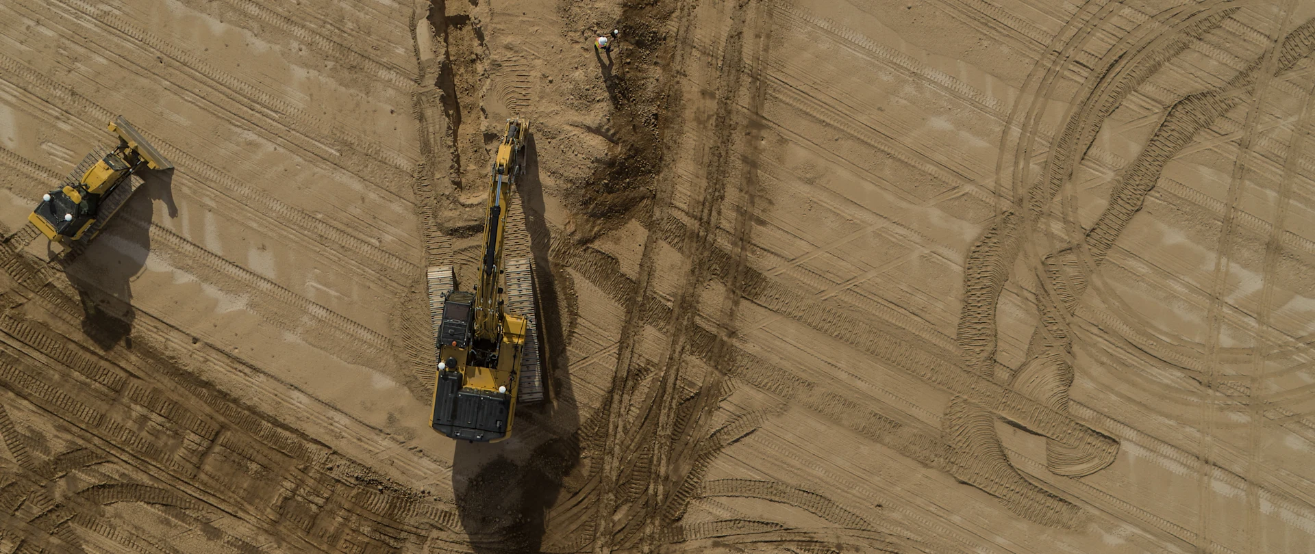 Aerial view of an excavator and bulldozer on a sandy construction site, featuring Trimble Earthworks machine control technology.