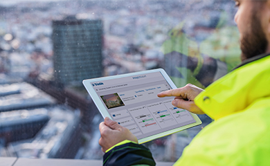 A construction worker uses a tablet displaying the Trimble Insight dashboard with a blurry city skyline in the background.
