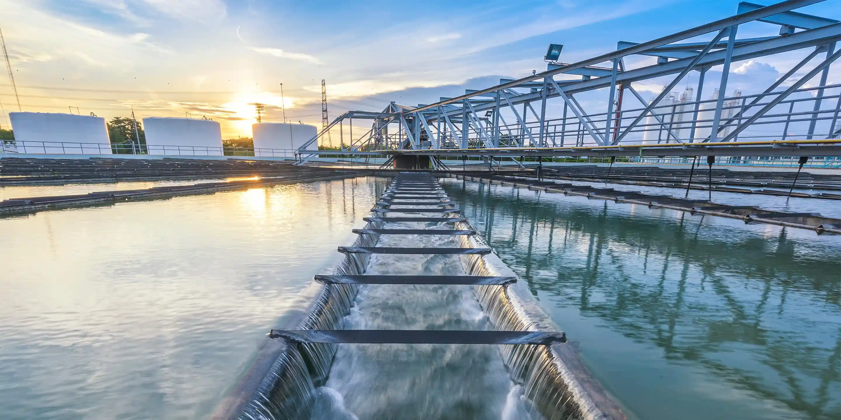 Water treatment plant at sunset, with a long channel of water flowing towards the foreground.