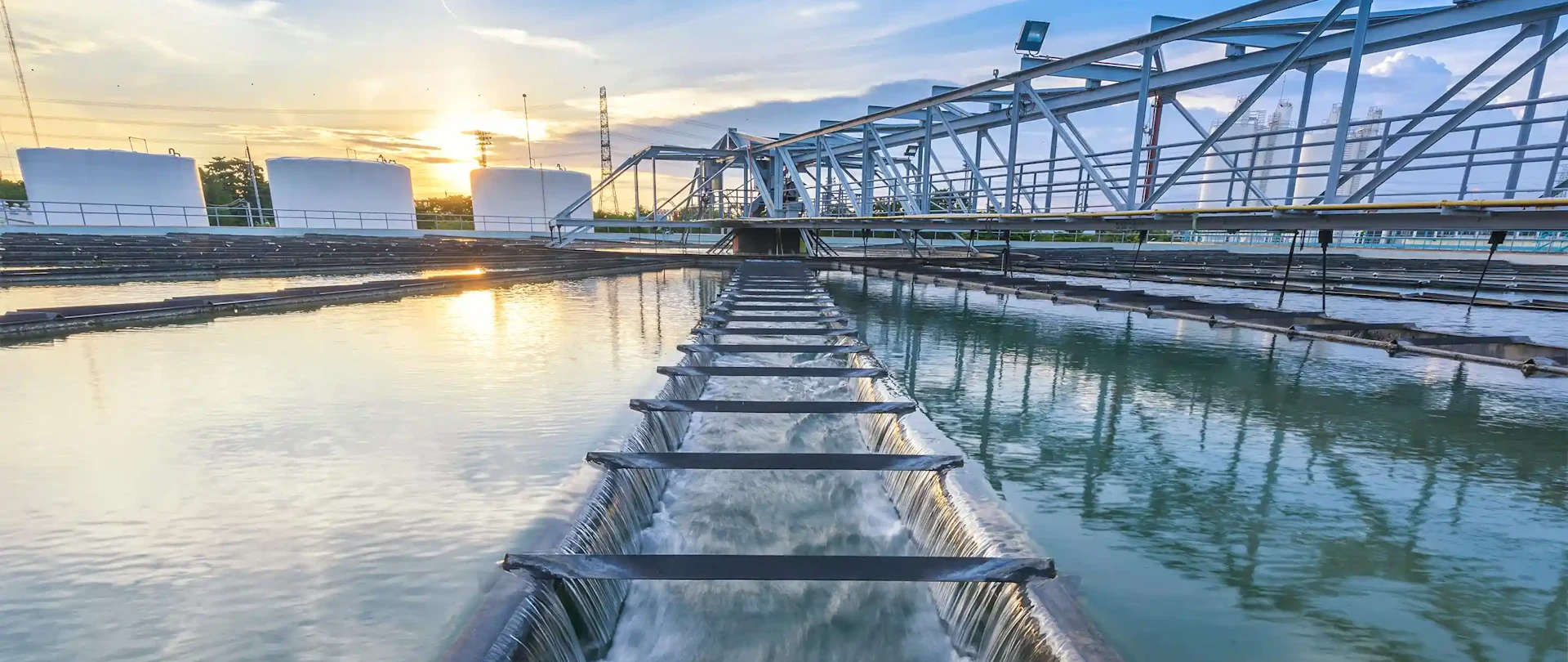 Water treatment plant at sunset, with a long channel of water flowing towards the foreground.