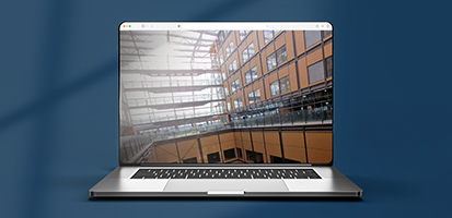 Laptop screen showing an NHS Midland Metropolitan hospital construction case study in a modern building.