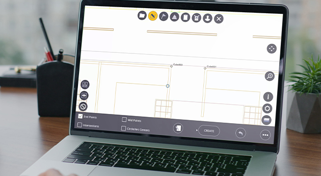 A laptop on a desk displays Trimble FieldLink software with building layout plans and snap point tools for construction planning.