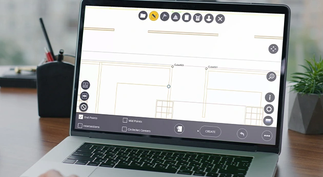 A laptop on a desk displays Trimble FieldLink software with building layout plans and snap point tools for construction planning.