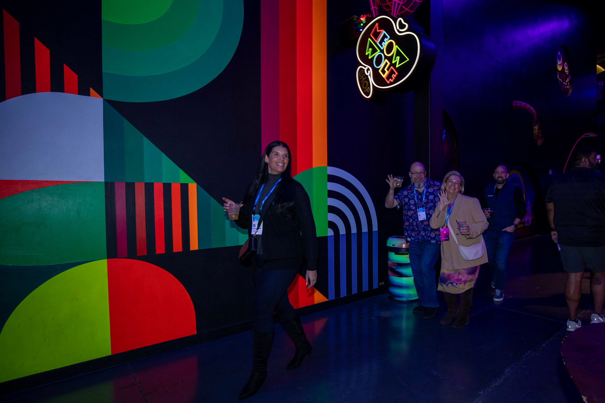 Dimensions attendees enter the Customer Appreciation Party at AREA15 while smiling and waving to the camera.