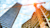 Low-angle shot of an orange construction crane between a glass skyscraper and a building under construction with orange graphic line overlays.