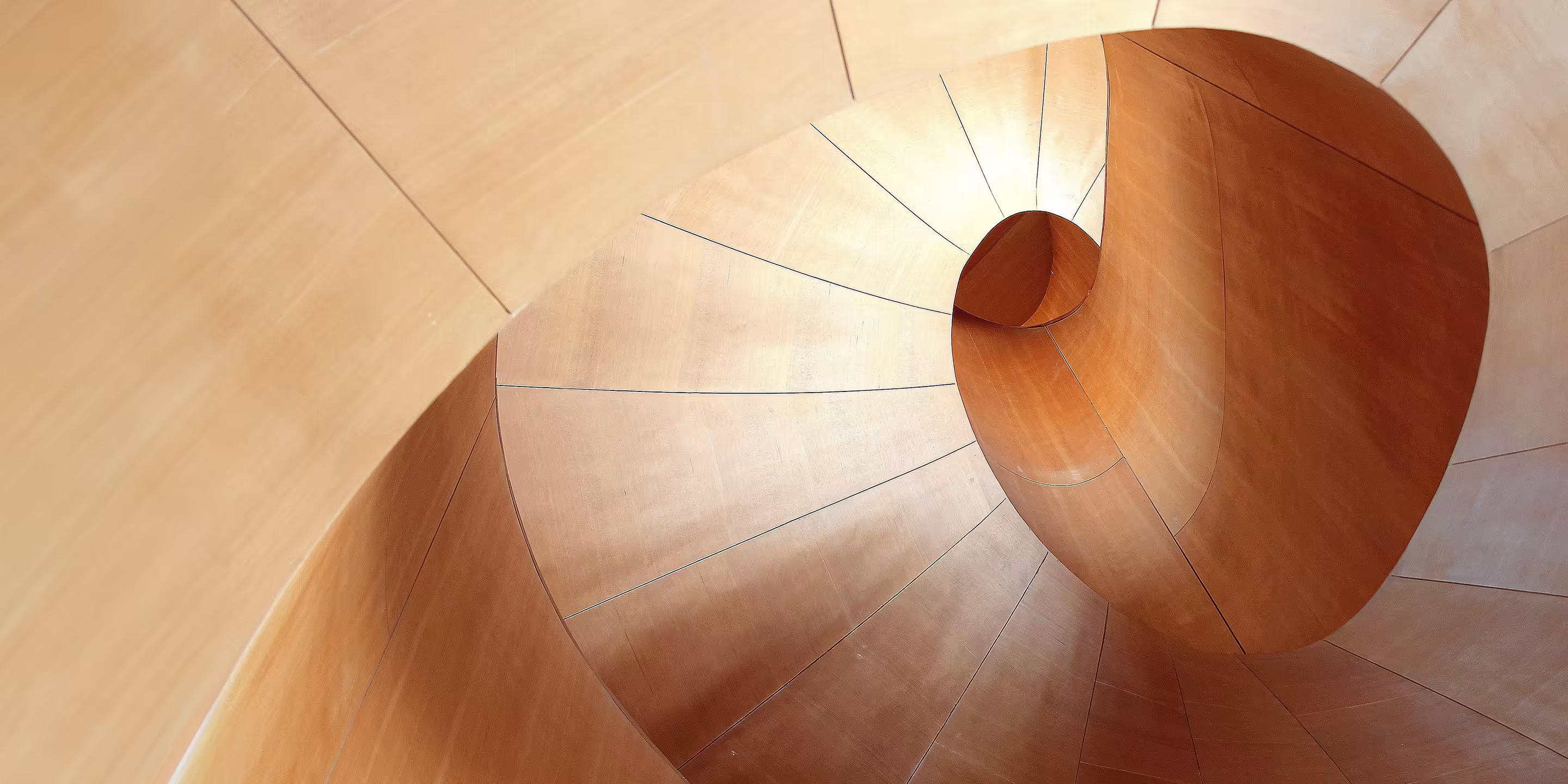 A top-down view of the sculptural wooden spiral staircase at the Art Gallery of Ontario in Toronto, designed by architect Frank Gehry.