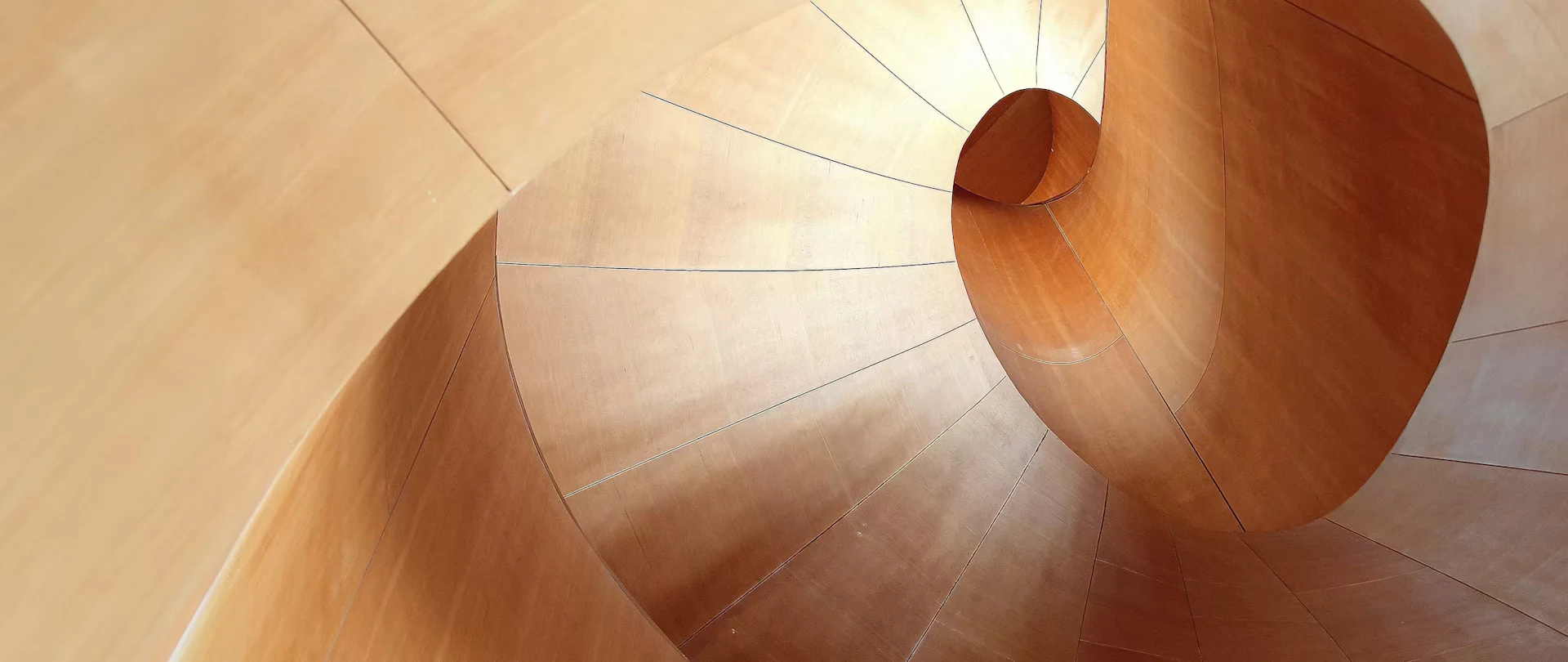 A top-down view of the sculptural wooden spiral staircase at the Art Gallery of Ontario in Toronto, designed by architect Frank Gehry.