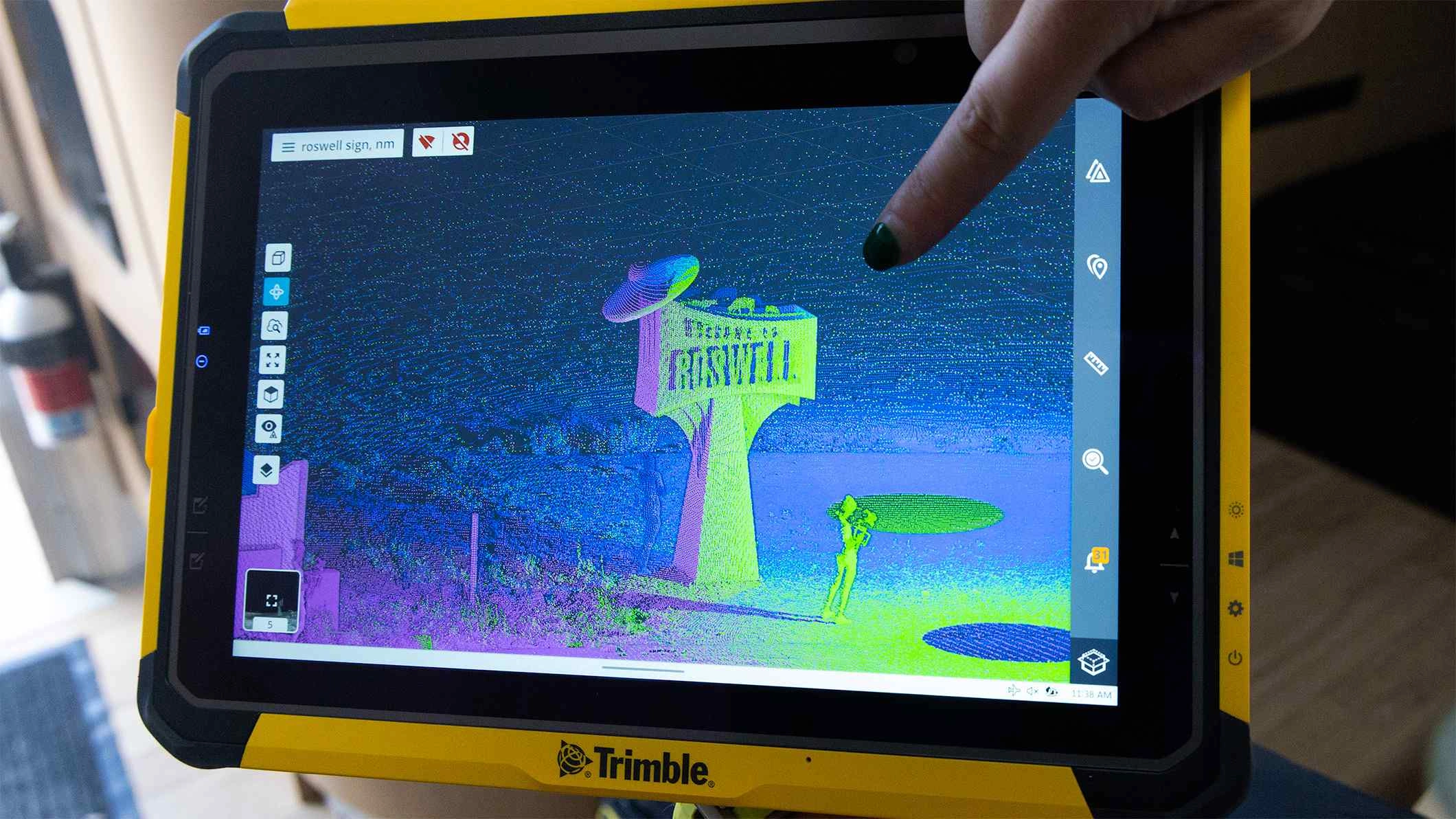 Ein Finger zeigt auf eine 3D-Punktwolke des Roswell-Schildes auf einem robusten Trimble-T10-Tablet, auf dem Trimble Perspective geöffnet ist.