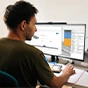 Een man zit aan een bureau, gefocust op een groot computerscherm waarop BIM-objecten uit MEPcontent worden weergegeven.
