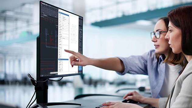 Two people review a technical MEP design in Stabicad for AutoCAD on a monitor.