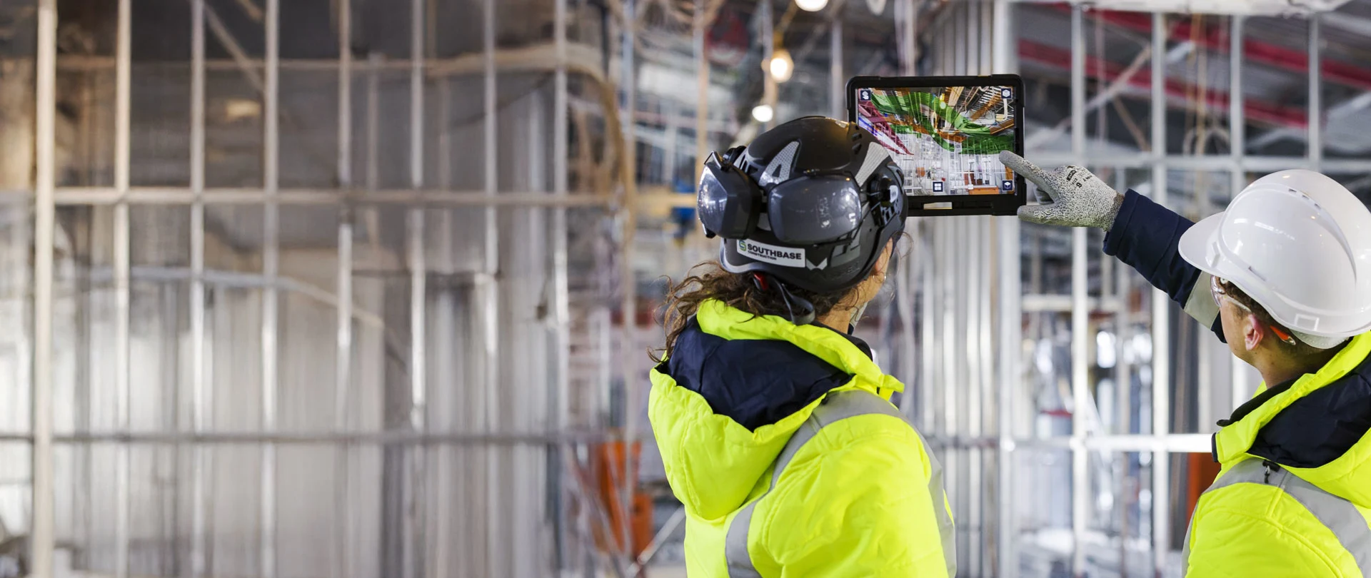 Two construction workers using a tablet with augmented reality on a job site