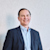 Phillip Sawarynski, CFO of Trimble, wearing a navy blazer and light blue shirt, smiling against a textured white wall.