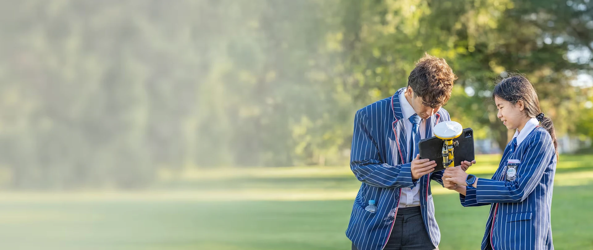 Two students in striped blazers using Trimble SiteVision outdoors during a career day in Christchurch, NZ
