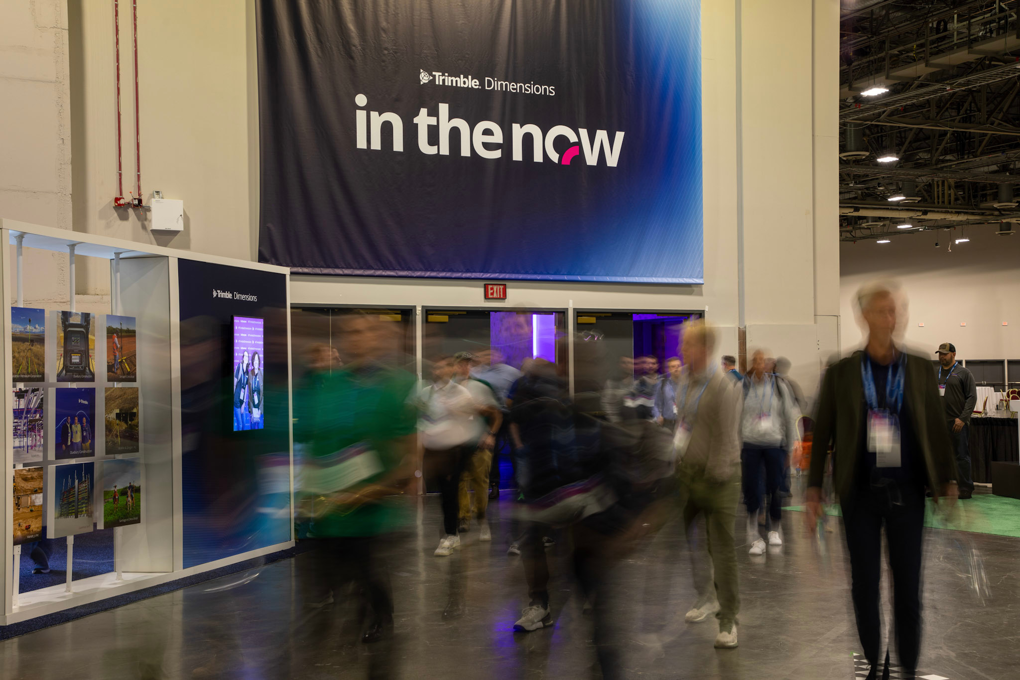 A blurred view of attendees as they enter the Expo Hall under a Trimble Dimensions branded banner.