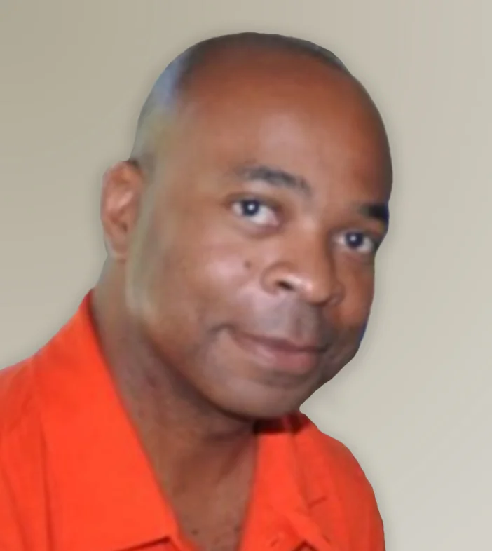 A close-up headshot of a Kevin Eison from Microsoft in an orange collared shirt, smiling gently with a slight head tilt against a plain light background.