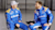 NASCAR drivers Ryan Preece and Chris Buescher in blue RFK Racing suits with Trimble sponsorship, discussing in a garage.
