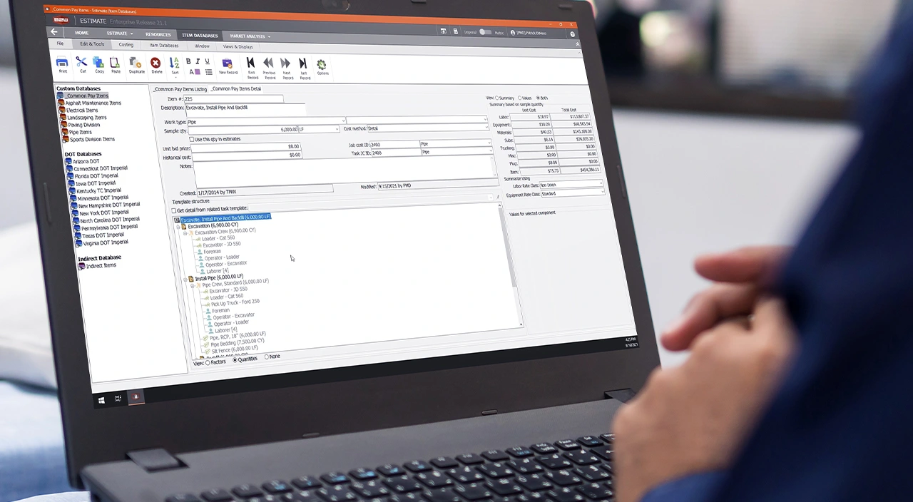 A person uses Trimble's B2W Estimate Enterprise software on a laptop to manage construction project costs and data.