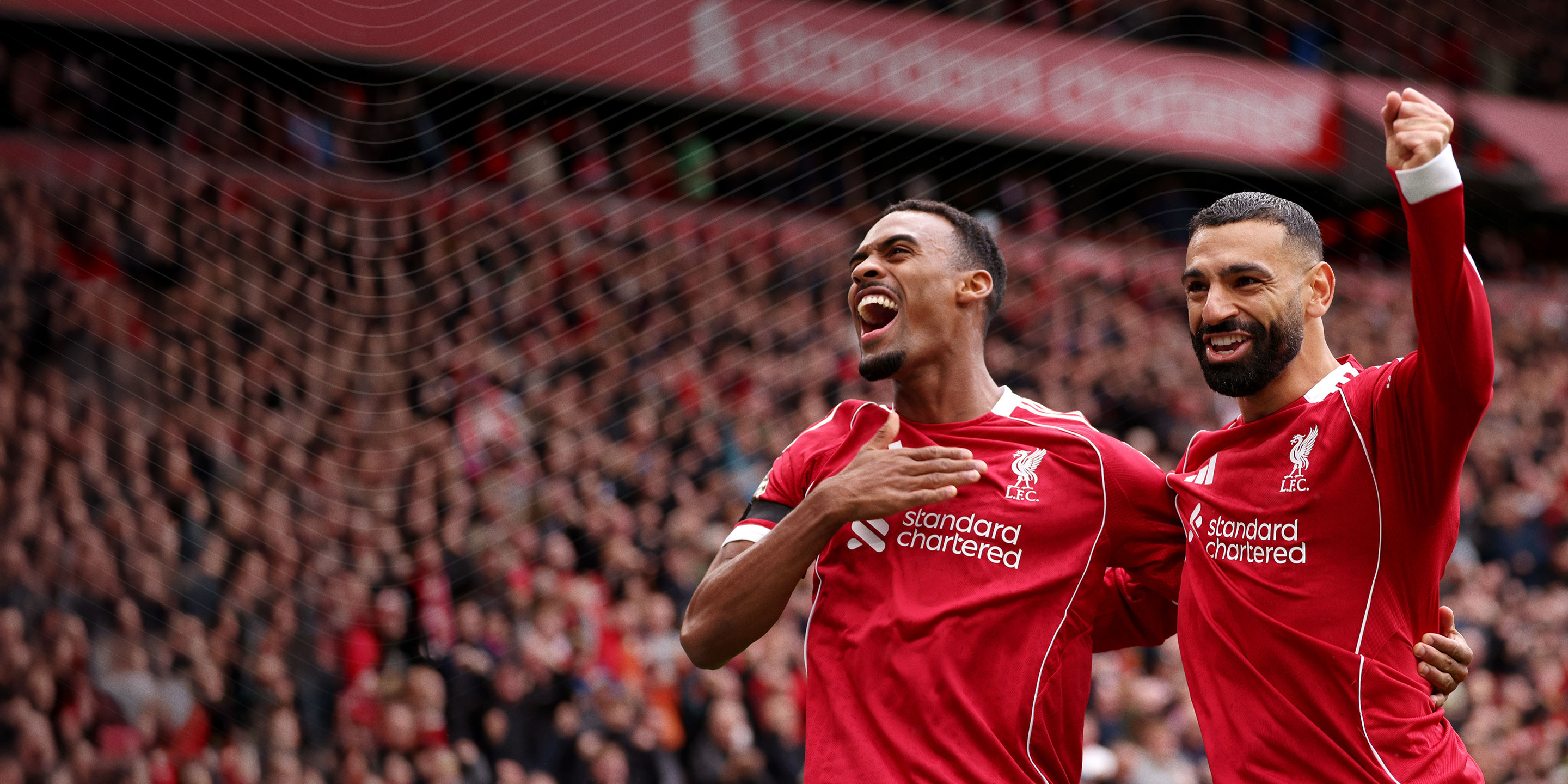 Deux joueurs du Liverpool Football Club fêtant la victoire avec une foule de supporters flous en arrière-plan.