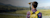 Man using Trimble Geospatial equipment looking at field and mountains