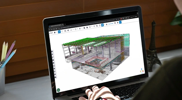 A person uses a laptop to view a detailed 3D architectural model within the Trimble Connect web-based BIM collaboration platform.