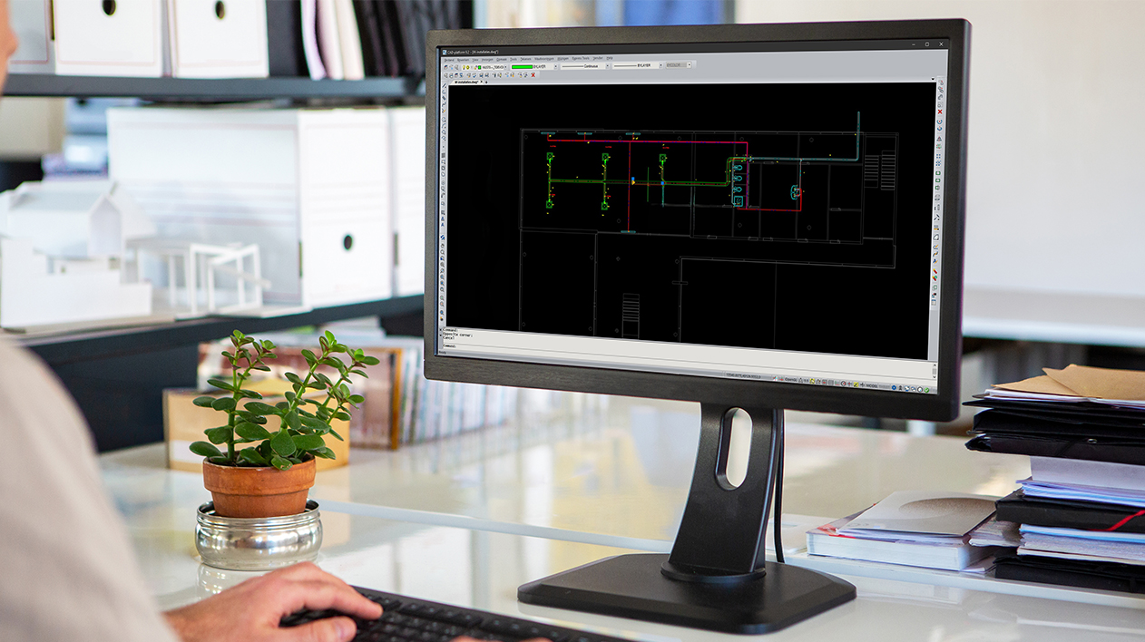 A monitor displaying Stabicad for IntelliCAD software with a 2D MEP layout on a desk.