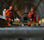 Two workers in orange safety gear use a Trimble GEDO CE track measurement trolley to survey railway tracks inside a tunnel.