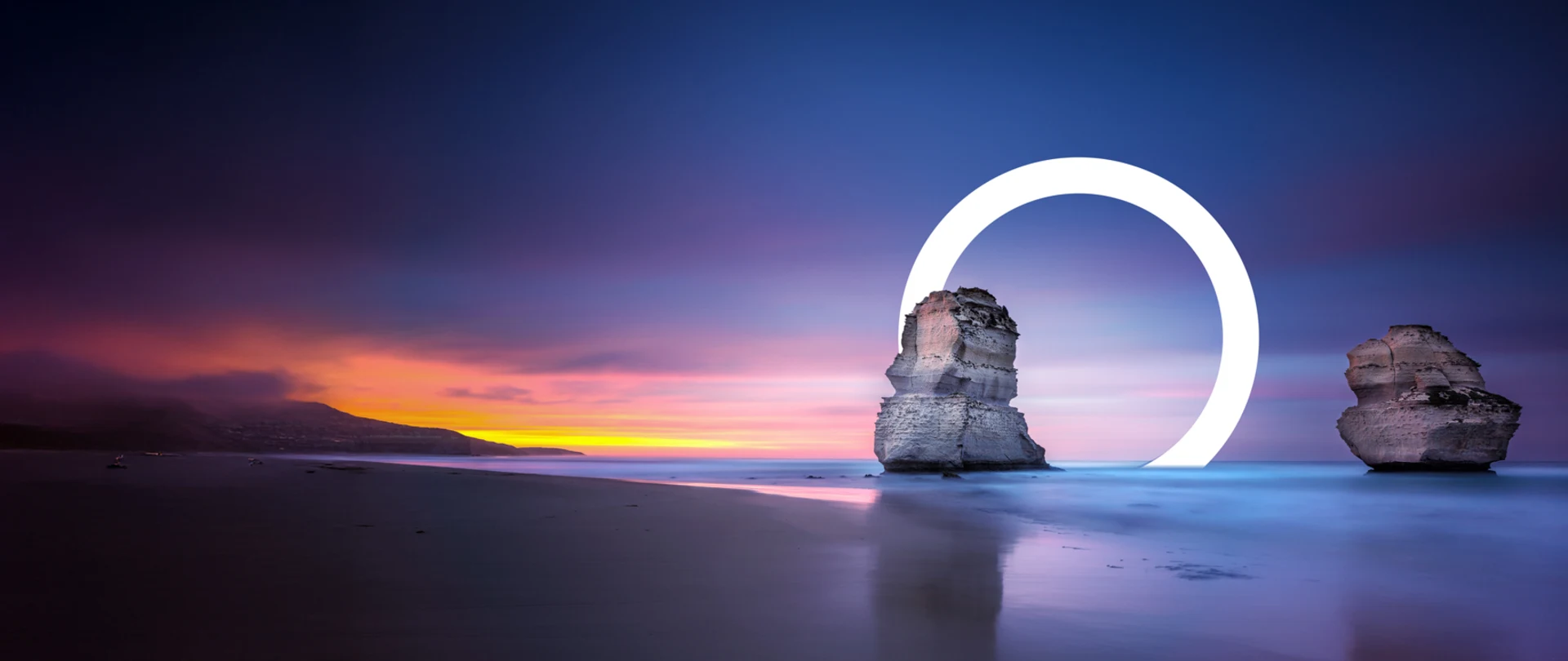 A serene beach sunset with two rock formations, one encircled by a glowing ring.
