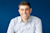 Headshot of Mark Schwartz, SVP of Trimble, smiling in a blue and white checkered shirt against a solid blue background.