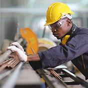 Worker in safety gear inspecting read and blue pipes