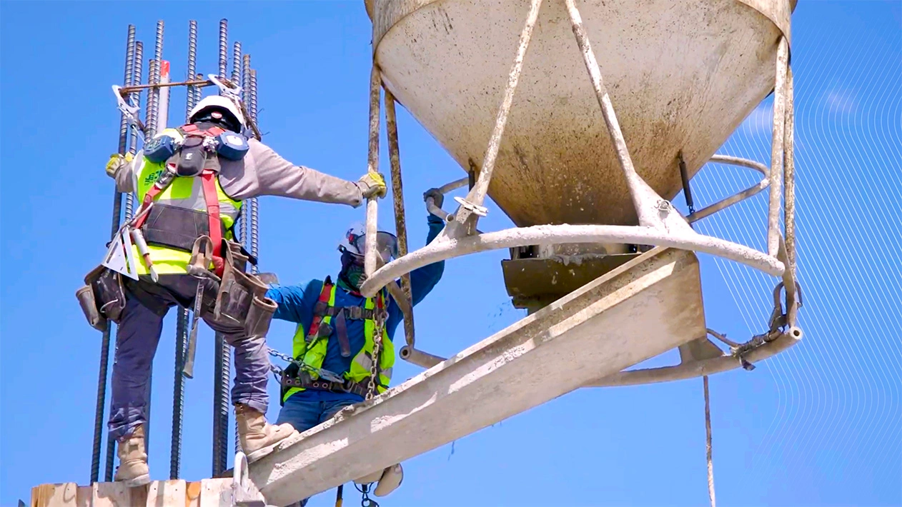 Two JE Dunn employees performing a concrete pour from scaffolding on a jobsite in Austin, Texas, demonstrating standardized national processes.