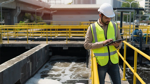 Service engineer checking on waste water treatment plant using tablet