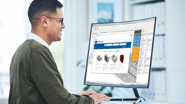 A man smiling at a monitor displaying Stabicad for Revit and the MEPcontent browser with various HVAC component models.