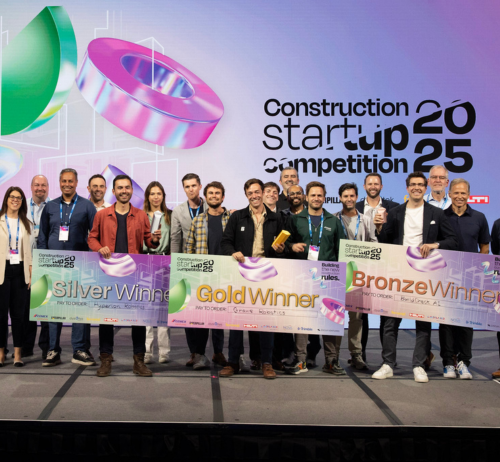 A group poses on stage holding large ceremonial signs for Silver, Gold, and Bronze winners at the 2025 Construction Startup Competition. In Construction Startup Competition.jpg, a large event backdrop stands behind the smiling participants.