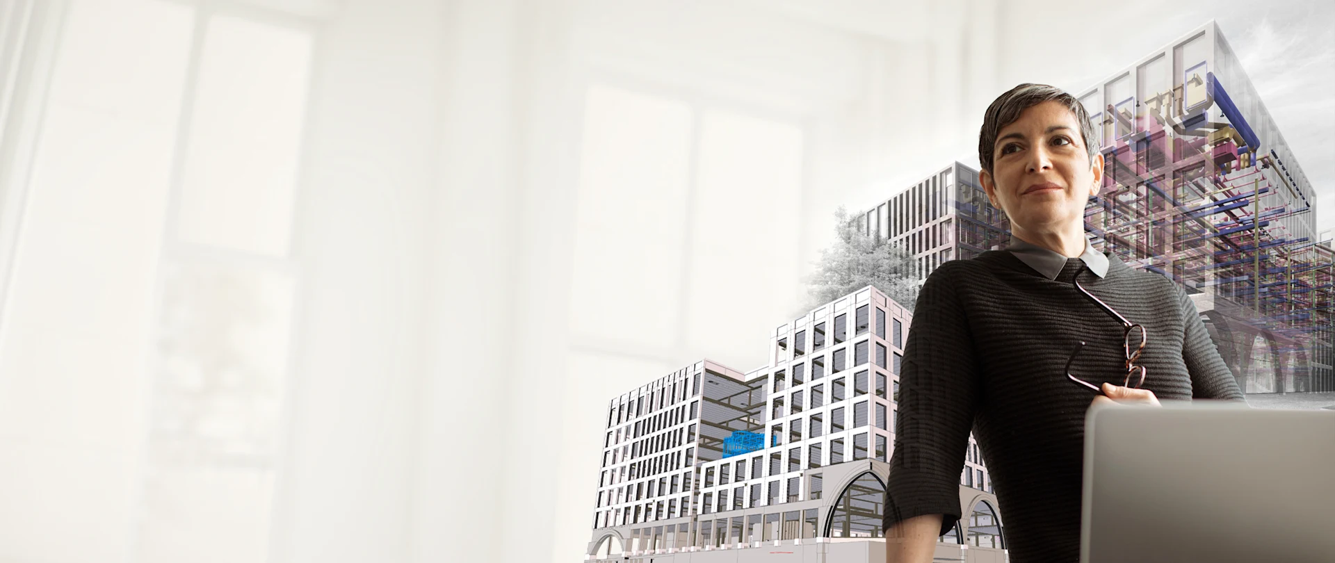 A woman stands with a laptop, overlaid with 3D building models illustrating Trimble's architectural and BIM design software solutions.