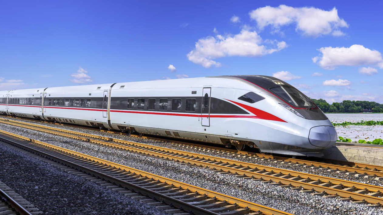 A white high-speed train with red accents is moving on a track under a blue sky with scattered clouds.