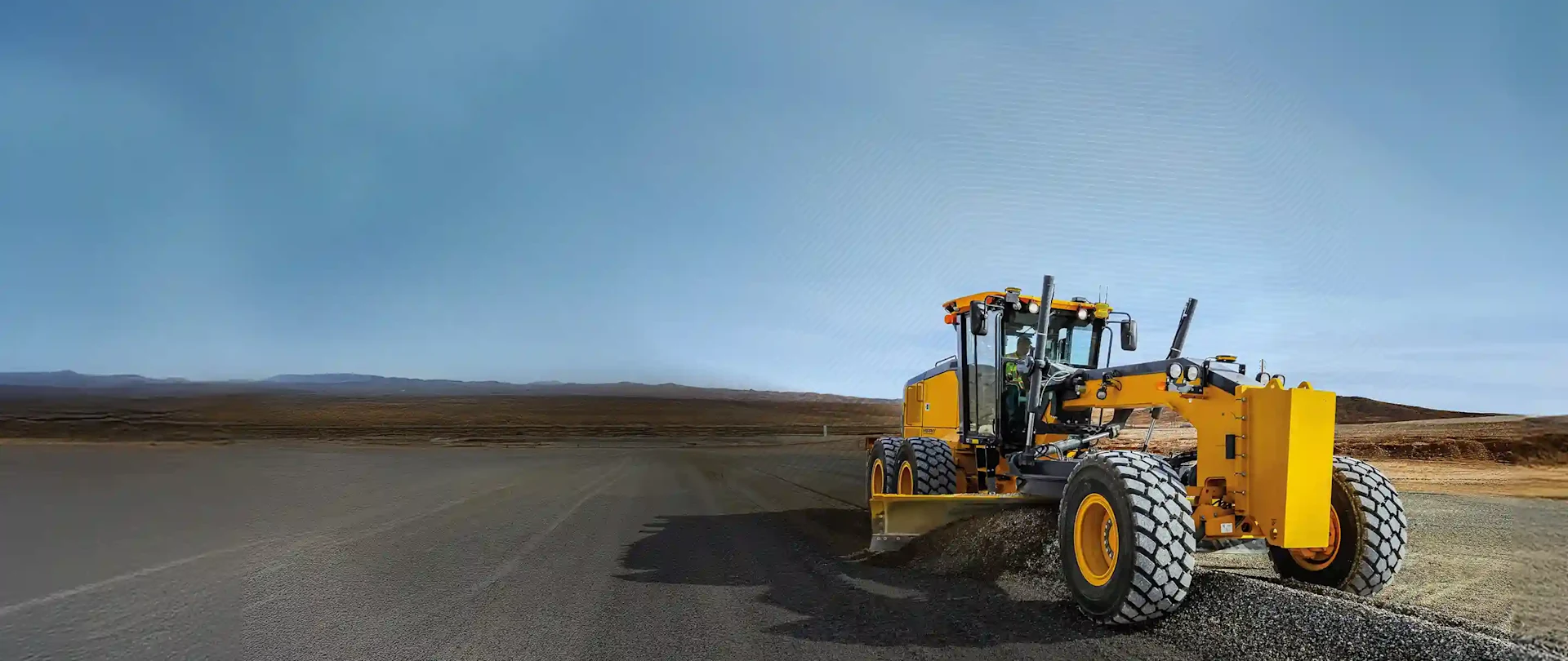 Gelber Motorgrader, der eine Straße ebnet, mit einem digitalen Raster, das die Trimble Earthworks Maschinensteuerungstechnologie darstellt.